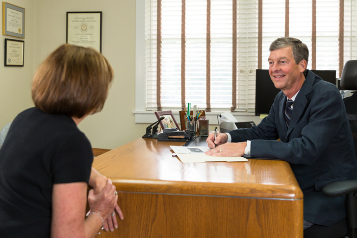 Man writing in file while speaking with client