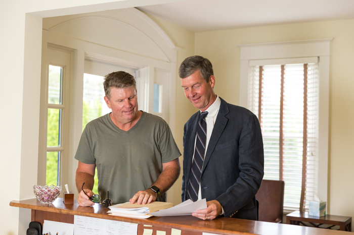 Two men reviewing files at front desk in lobby